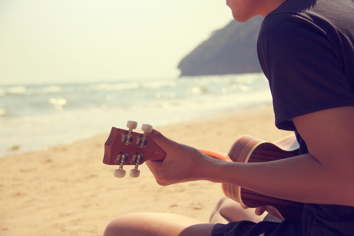 Person playing ukulele on the beach