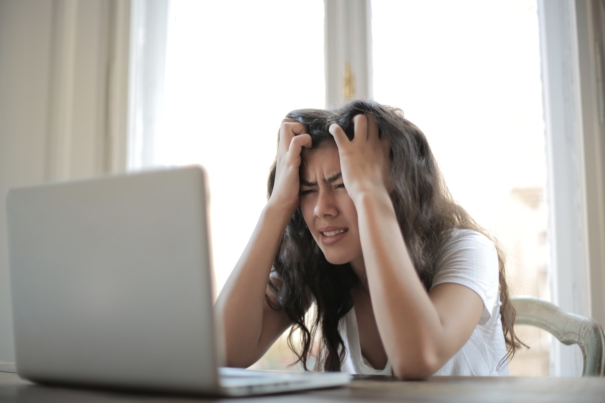 A young woman squints at her laptop screen.