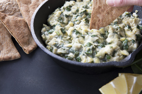 Pan with fresh vegan spinach artichoke dip and whole wheat pita bread.