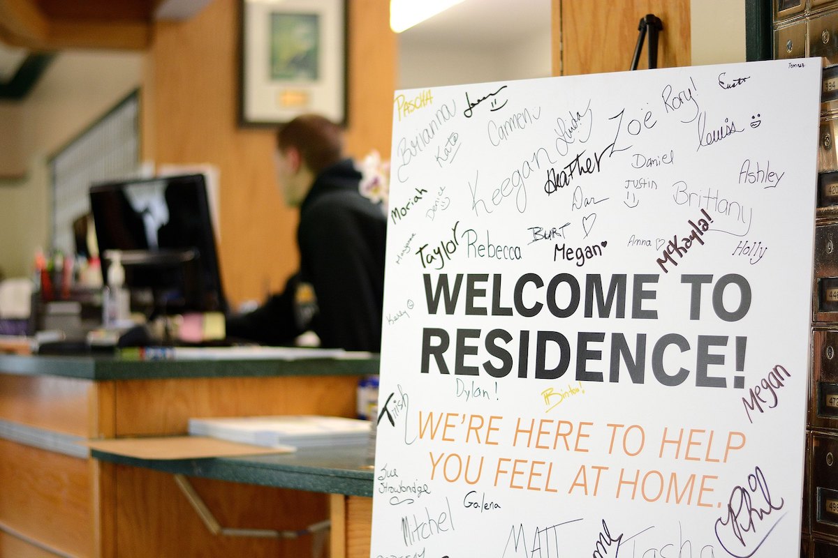 An image of a posterboard that reads "WELCOME TO RESIDENCE! WE'RE HERE TO HELP YOU FEEL AT HOME." The board is signed by many residence assistants.