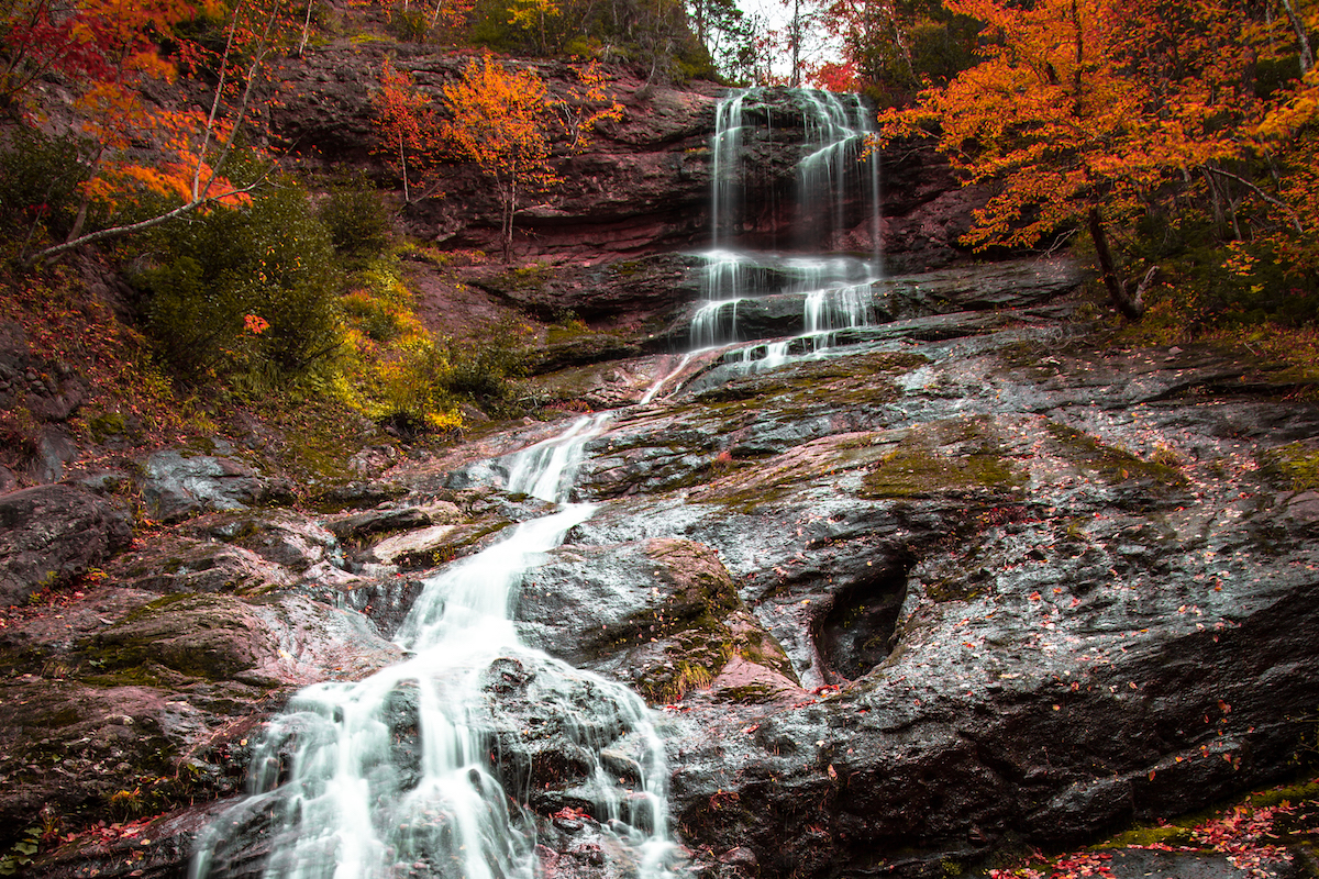 Waterfall moving down rocks surrounded by trees with colourful leaves