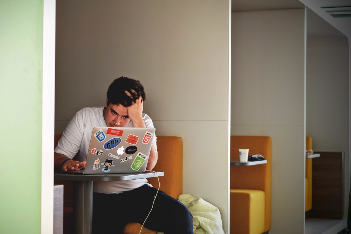 Male student sitting in front of a laptop looking stressed