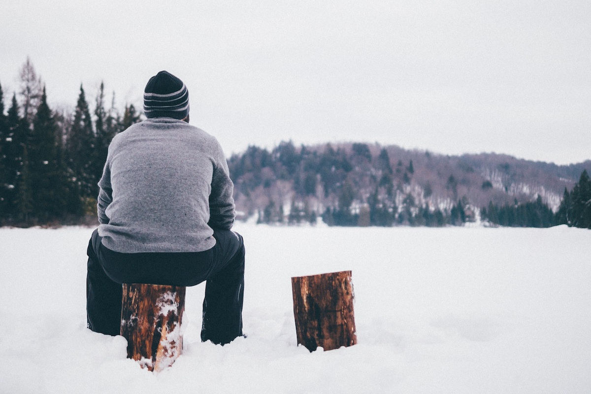Person sitting on a log stump in a snowy landscape