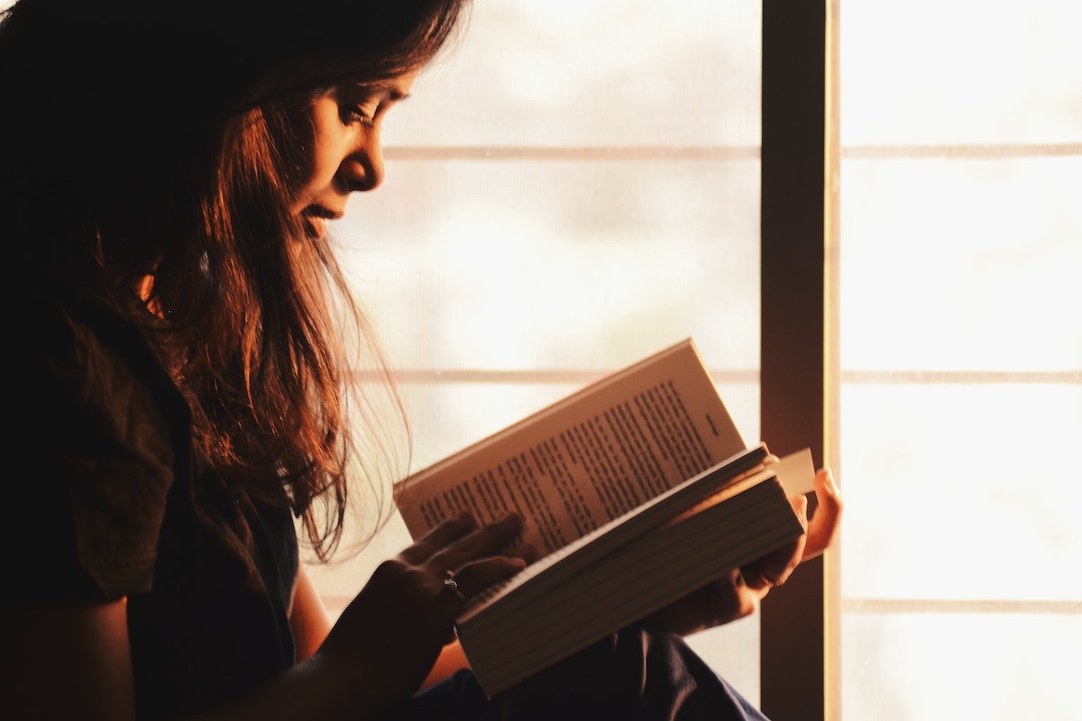 Woman reading a book in front of a window