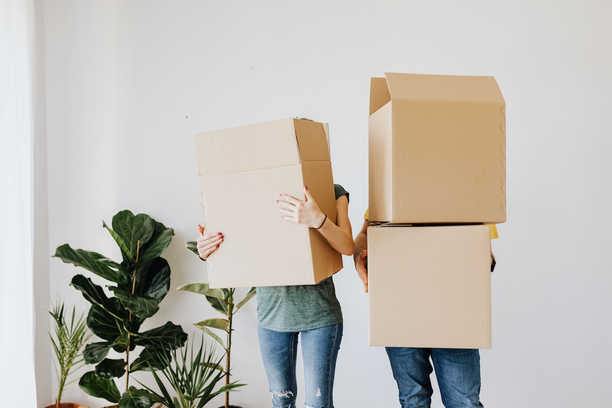 Two people holding large boxes that are obscuring their faces.