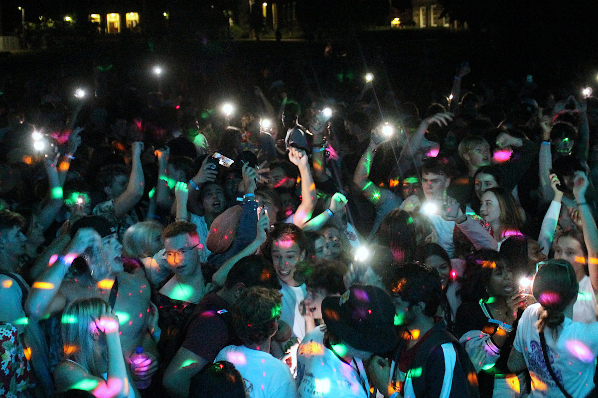 Large crowd of students dancing outside with coloured lights