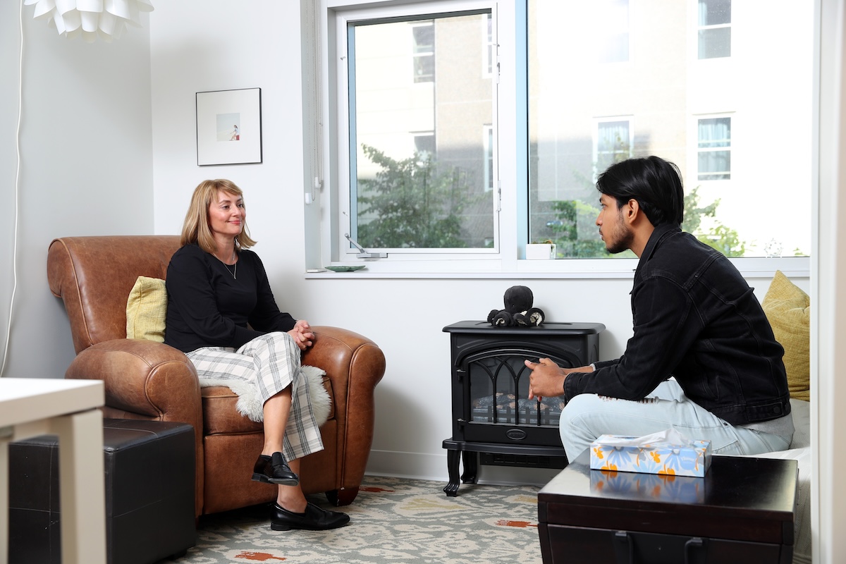 A university student sitting across from a mental health counsellor in a comfortable room
